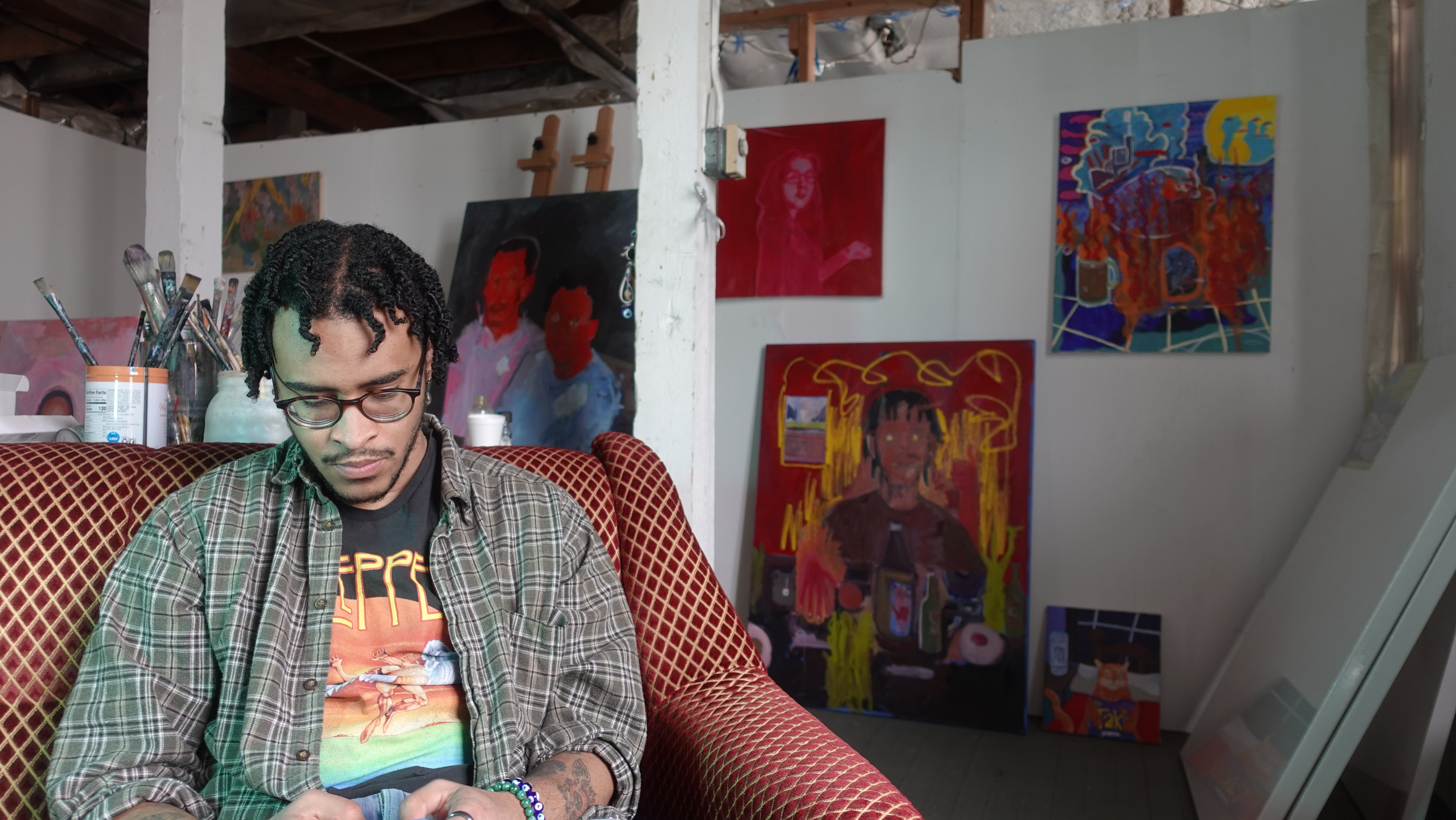 Jason Correia seated in his studio surrounded by paintings