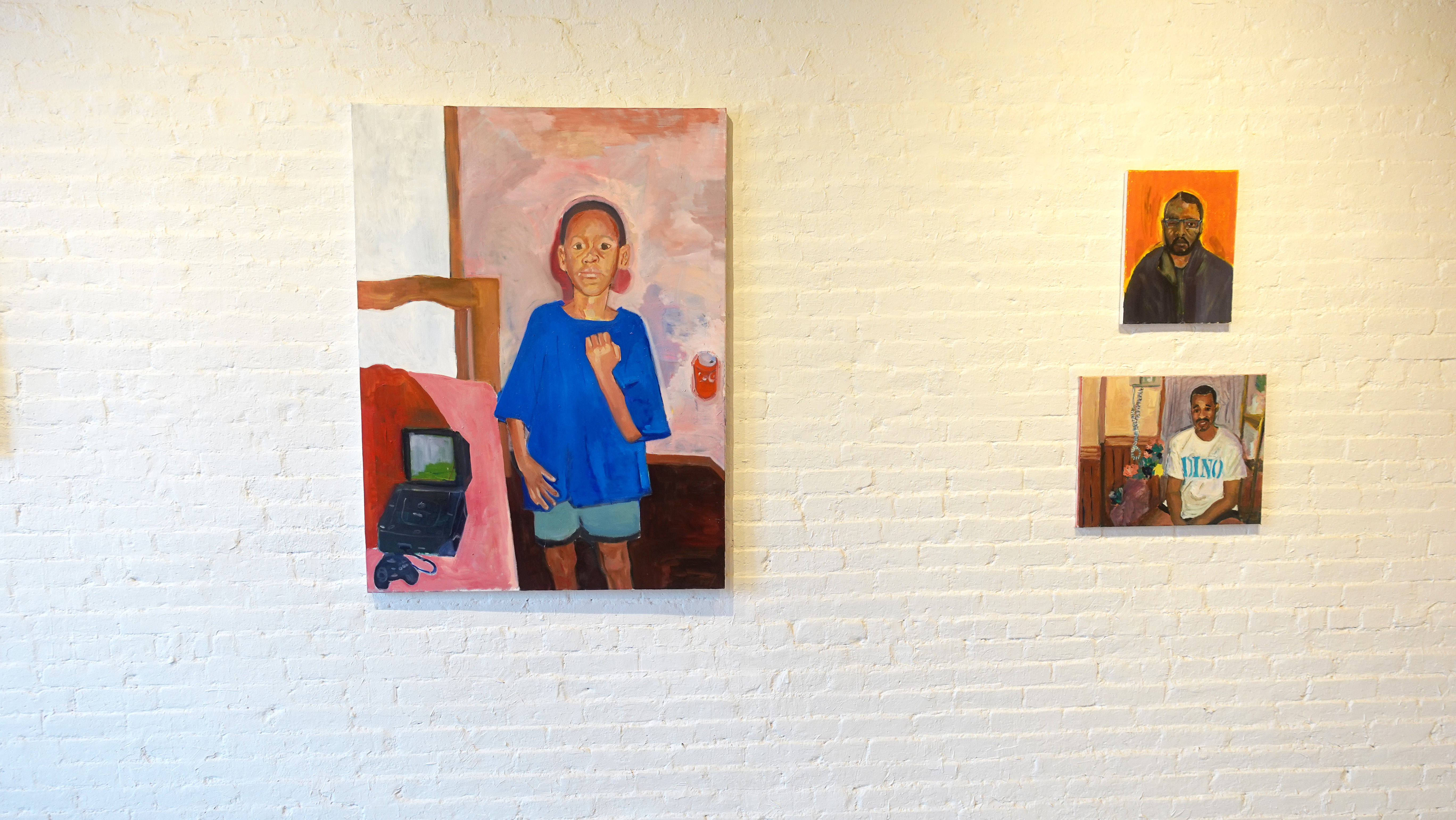 Three paintings from Love Is Horror installed on a white brick gallery wall