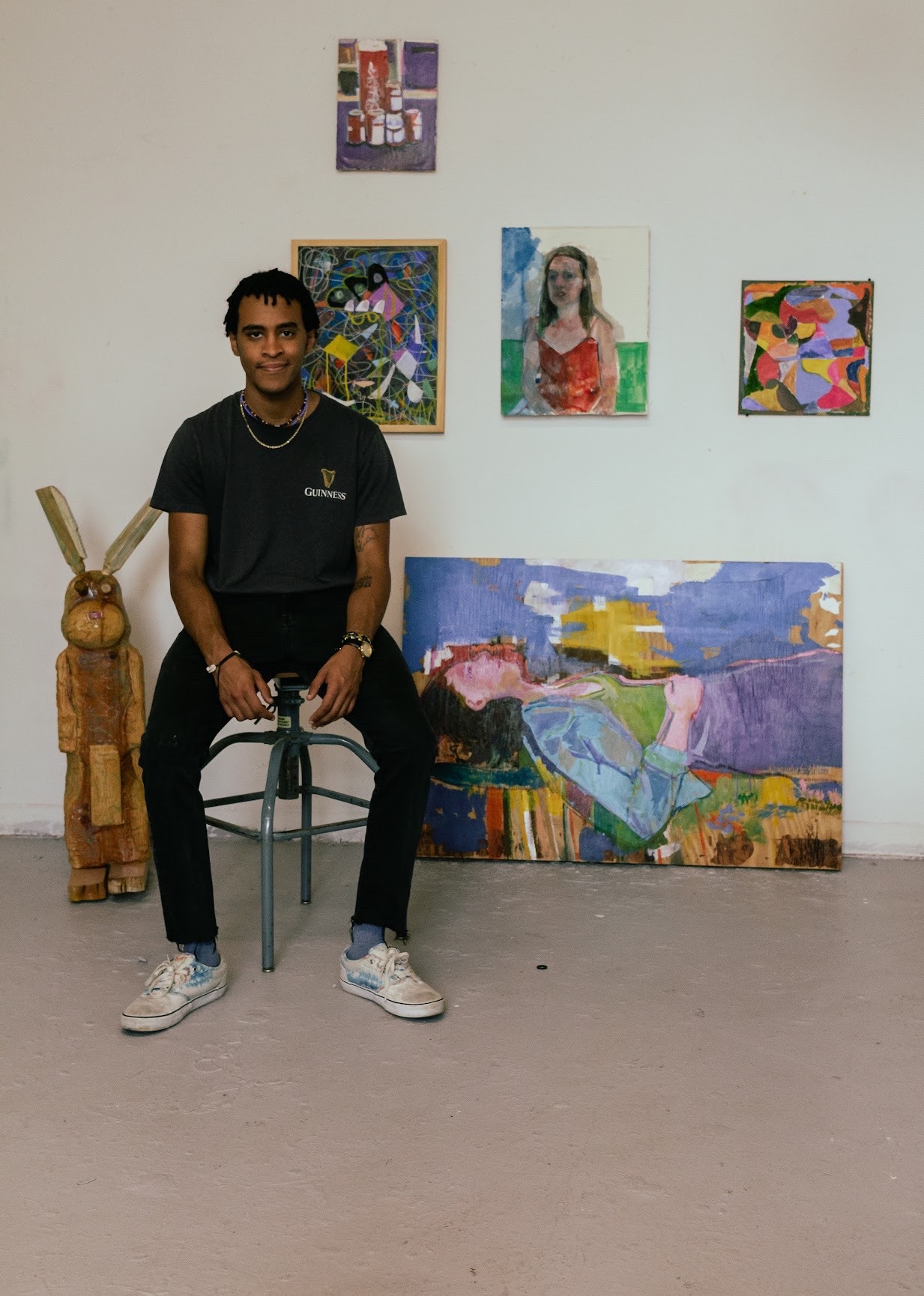 Jason Correia seated in his studio surrounded by paintings